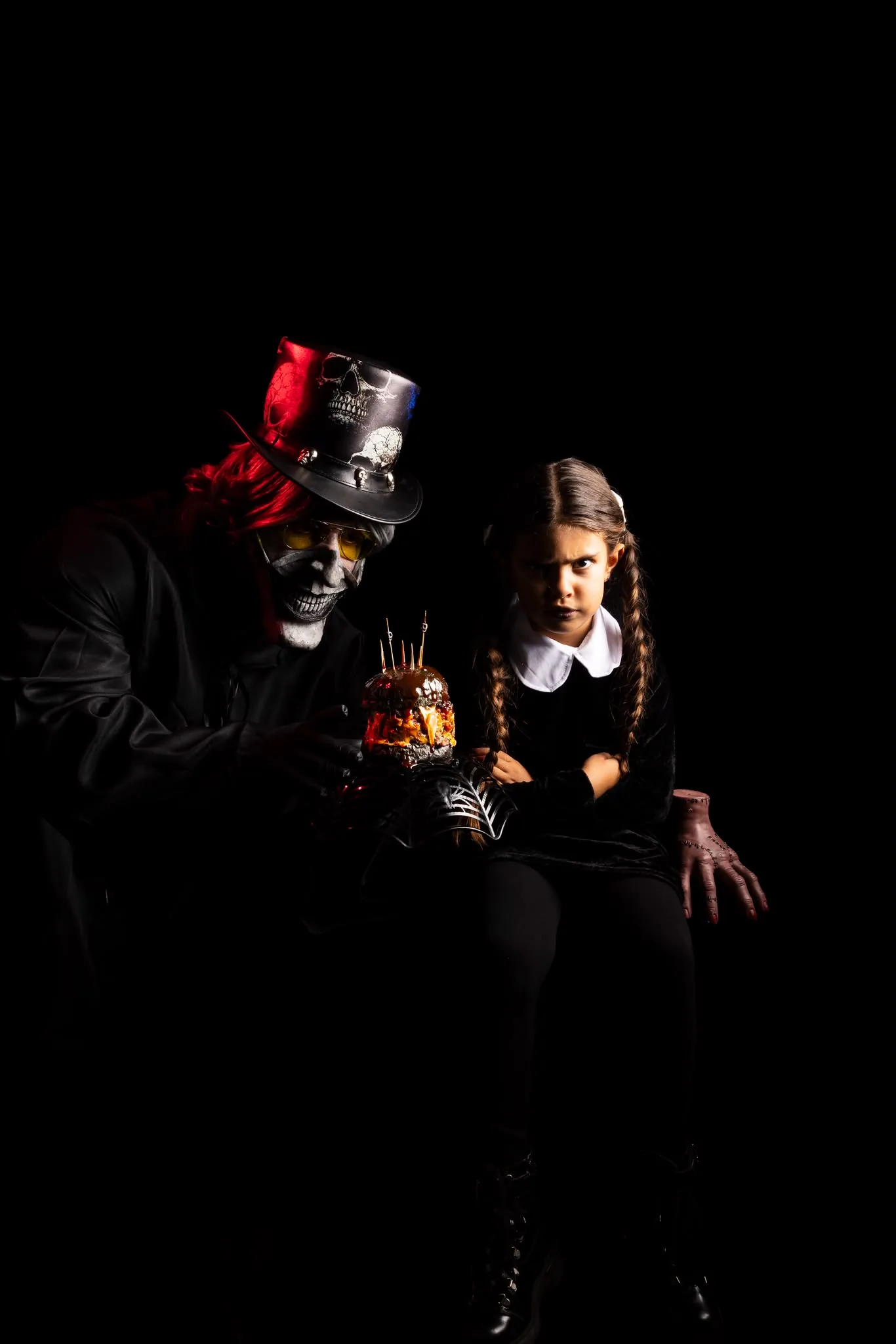 El Barón, con chistera y cara de calavera, ofrece la VUDÚ a una niña vestida de negro con coletas